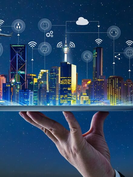 Symbolbild Digitalisierung: Eine Hand hält ein Tablet auf dem eine digital vernetzte Stadt steht.