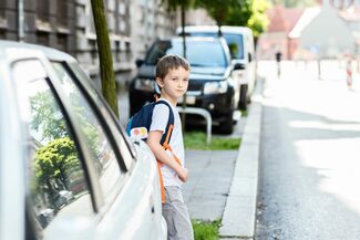 Grundschüler wartet an einer Straße, um sie zu überqueren