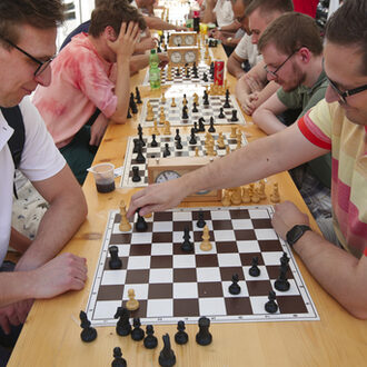 Menschen spielen Schach an Schachbrettern.