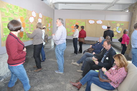 Teilnehmer der Veranstaltung Visionen heften Zettel an die Pinnwand