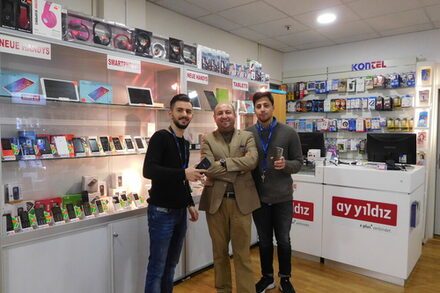 Sait Özcan mit Mitarbeitern in seinem Mobilfunkladen