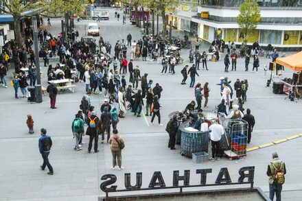 Menschen stehen auf einem Platz in der Innenstadt von Offenbach.
