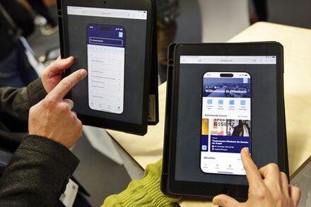 Zwei Personen testen eine App auf einem Tablet.