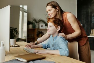 Mutter und Sohn vor einem Computer, Mutter legt ihre Hand auf seine Schulter