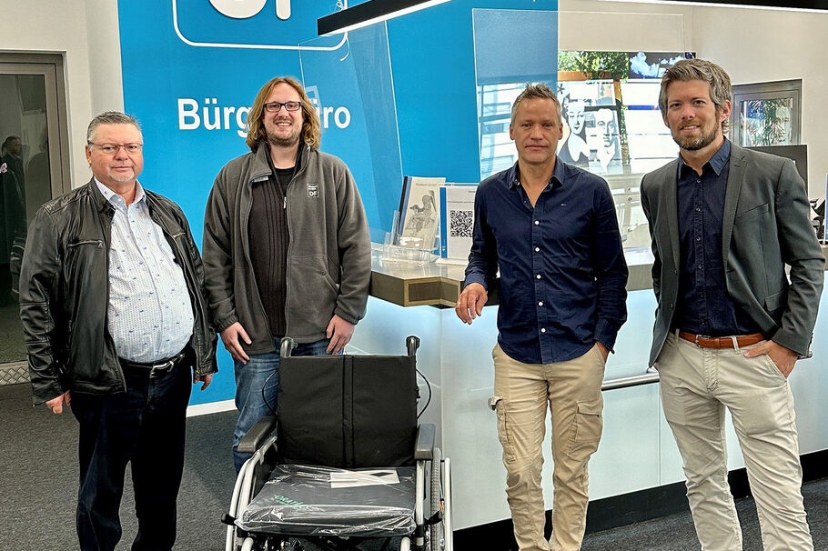 Vier Männer stehen mit einem Rollstuhl im Bürgerbüro Offenbach.