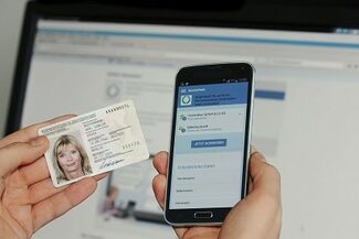 Mobiles Endgerät mit geöffneter App und Hand mit Personalausweis