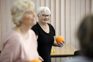 ältere Dame mit einem orangenen Softball