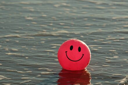 Ein Ball mit einem lachen Gesicht liegt im Wasser.