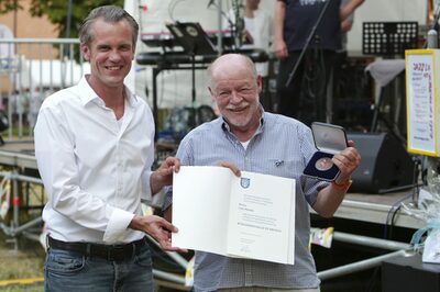 Oberbürgermeister Dr. Schwenke mit Lutz Plaueln, der die Bürgermedaille und die Urkunde in der Hand hält.