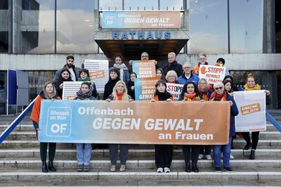 Personen stehen am Rathaus und halten ein Banner "Offenbach gegen Gewalt an Frauen"