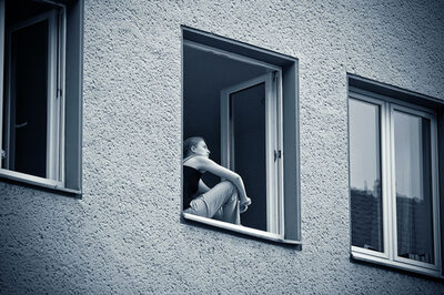 Eine Frau sitzt an einem geöffneten Fenster.