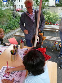 Bürgermeisterin Sabine Groß schaut zwei Mädchen dabei zu, wie diese an einem Tisch Bilder ausmalen.