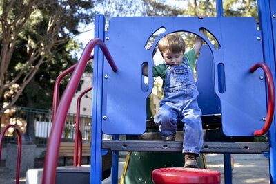 Ein Kind klettert auf dem Spielplatz auf einem Klettergerüst herum.