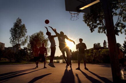 Eine Gruppe junger Erwachsener spielt Basketball im Mainuferpark.
