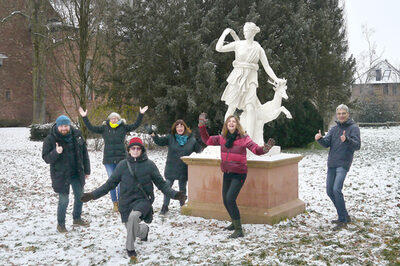 Eine Gruppe von Menschen steht im Schnee vor einer weißen Skulptur und freuen sich.