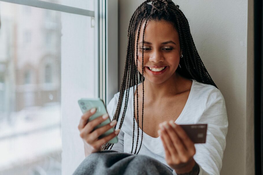 junge farbige Frau mit Handy und Kreditkarte