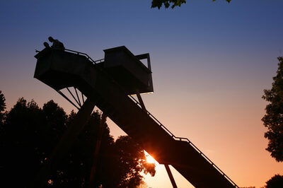 Die Sonne geht hinter der Aussichtsplattform Sichtturm im Wetterpark in Offenbach unter.