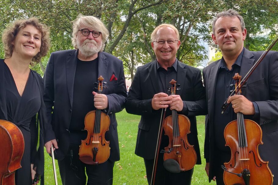 Die vier Musiker des Streichquartetts stehen in einem Park.