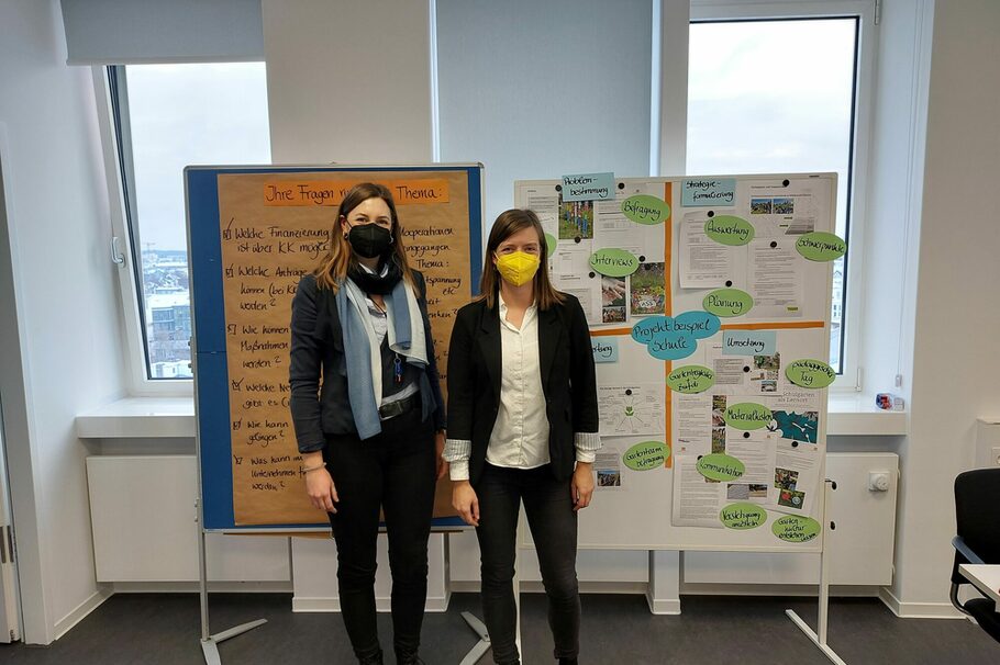 Zwei Frauen mit Masken vor Flipcharts