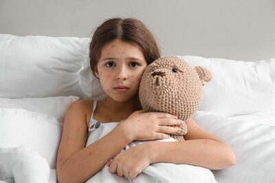 Mädchen mit Windpocken und Teddy im Bett