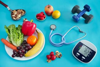 Das Foto zeigt gesundes Essen, Blutdruckmessgerät, Stethoskop und Hanteln.
