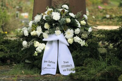 Ein Trauerkranz mit einer Schleife. Auf der Schleife steht "den Opfern der Luftangriffe" und "Stadt Offenbach am Main"