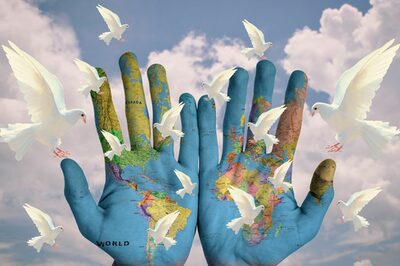 Hände auf der die Weltkarte gemalt ist, drumherum fliegende weiße Tauben.