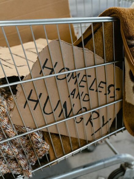 Einkaufswagen mit schild in englischer sprache homeless and hungry (obdachlos und hungrig)