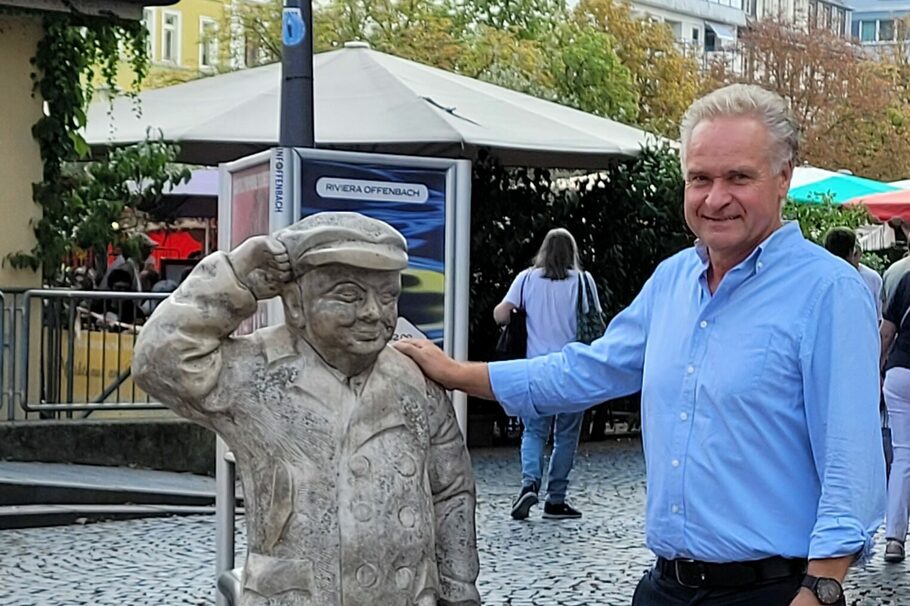 Ein Mann steht an einer Skulptur.