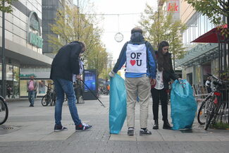 Drei Menschen mit Greifzangen und Müllsäcken in der Innenstadt