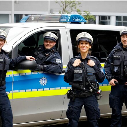 Vier Stadtpolizisten in und vor einem Dienstwagen
