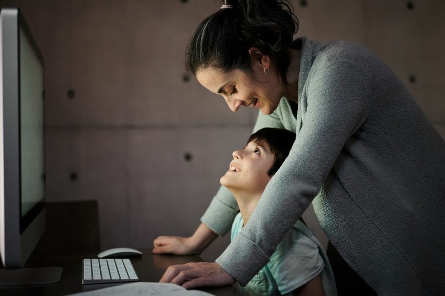 Mutter mit Sohn vor einem Computer.