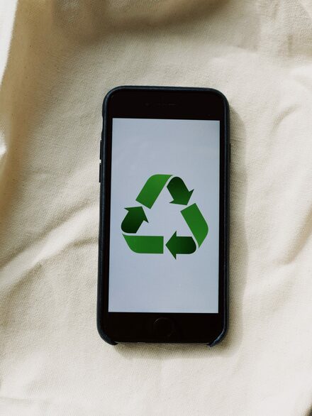 Recycling-Symbol auf einem Smartphone, darunter eine Stofftasche