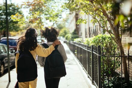 Zwei Schulkinder laufen zusammen auf dem Bürgersteig