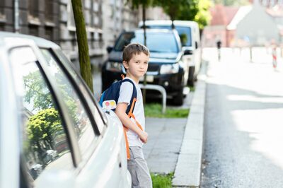 Grundschüler wartet an einer Straße, um sie zu überqueren