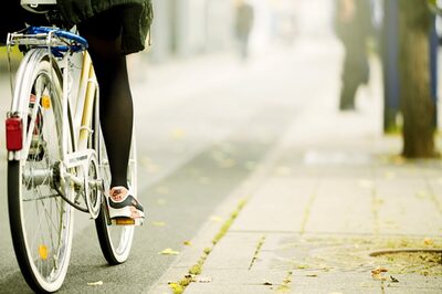 Zu sehen sind die Beine einer Frau auf einem Fahrrad.