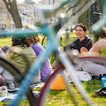 Eine Gruppe von jungen Menschen macht auf einer Wiese ein nach einer Fahrradtour ein Picknick.
