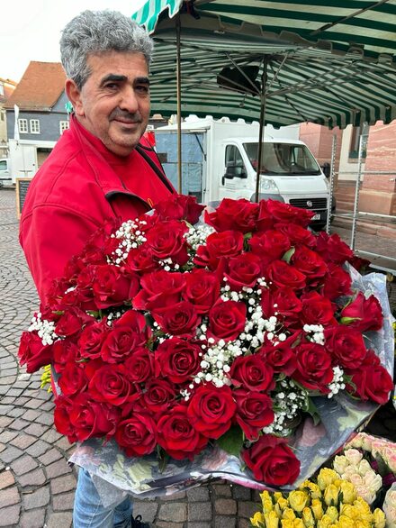 Antonio Palumbo zeigt einen üppigen Blumenstrauß mit roten Rosen.