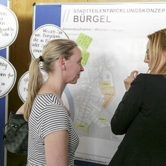 Zwei Frauen vor Plakatwand zum Stadtteilentwicklungskonzept Bürgel.
