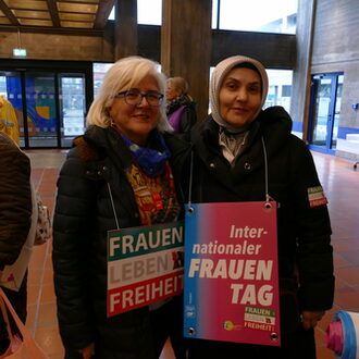 Zwei Frauen mit ihren Schildern im Rathaus