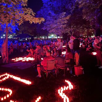 Lichterfest bei Nacht mit Menschen zwischen roten Kerzen.
