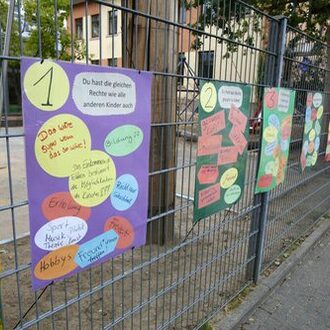 Die von den Kindern erstellten Plakate zu Kinderrechten hängen am Zaun.