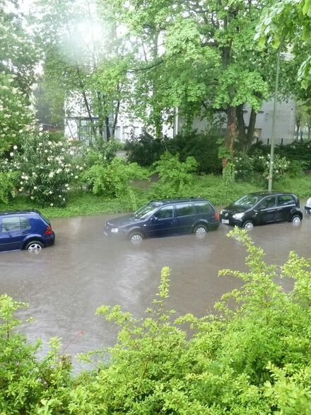 Autos stehen auf einer überfluteten Straße in Folge eines Starkregens.