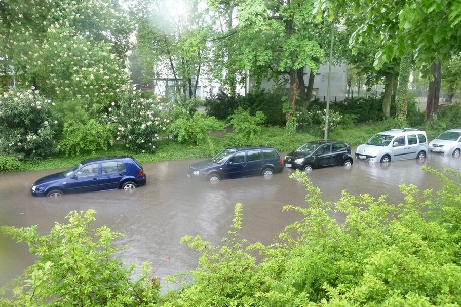 Autos stehen auf einer überfluteten Straße in Folge eines Starkregens.