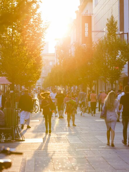 Menschen laufen in der Fußgängerzone, Licht von untergehender Sonne