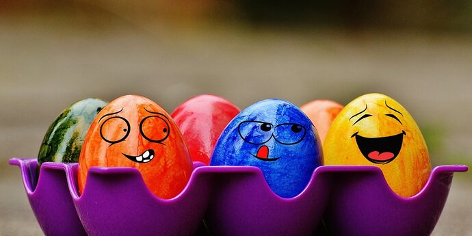 Bunte Ostereier mit lachenden Gesichtern in einem lila Eierkarton.