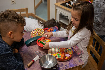 Kinder spielen mit einer Holz-Pizza in einer EKO-Kita