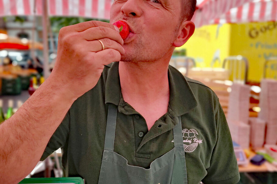 Ein Mann isst eine Erdbeere.