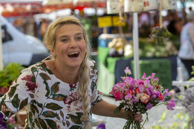 Birgit Kunz lacht  und hält einen bunten Strauß Blumen in der Hand.