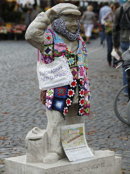 Statue Streichholzkarlchen mit einer Tasche gegen Fluglärm